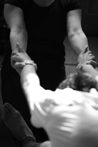 a black and white photo of a woman holding someone's hand