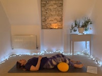 a woman laying on a yoga mat with a ball in front of her